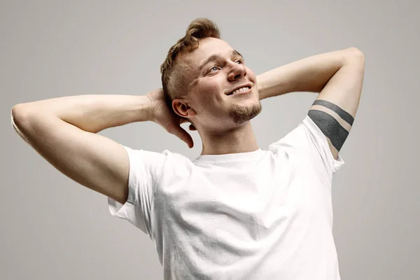 El hombre de negocios feliz de pie y sonriendo contra el fondo gris . — Foto de Stock