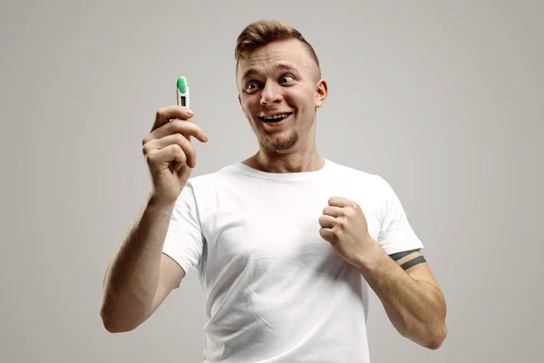 Happy man looking at pregnancy test at studio — Stock Photo, Image