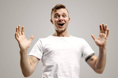 Şaşırmış görünen çekici adam gri izole genç