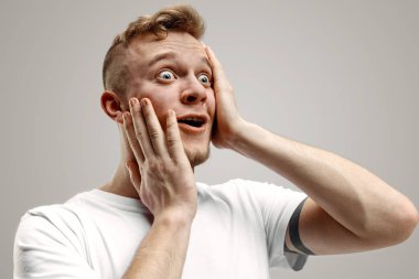 Şaşırmış görünen çekici adam gri izole genç