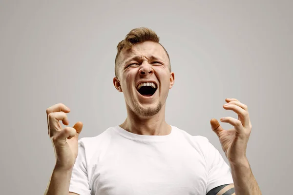 Молодий емоційно розлючений чоловік кричить на студійному фоні Гареї — стокове фото