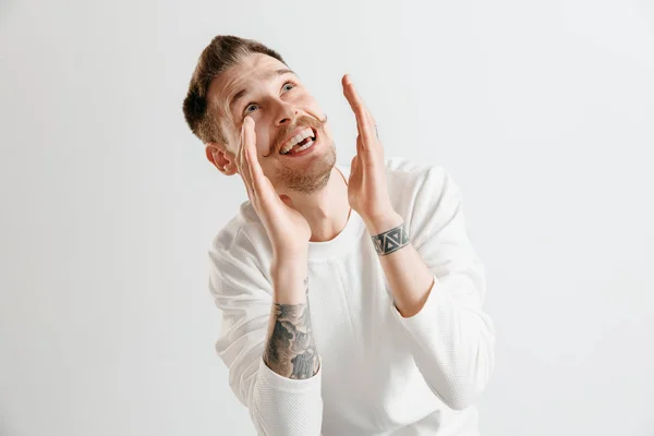 El hombre de negocios feliz de pie y sonriendo contra el fondo gris . — Foto de Stock