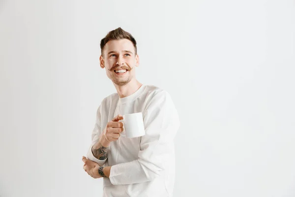 Kávészünet. Egy csésze kávé állva sötétszürke háttérrel rendelkező csinos, fiatal férfi — Stock Fotó