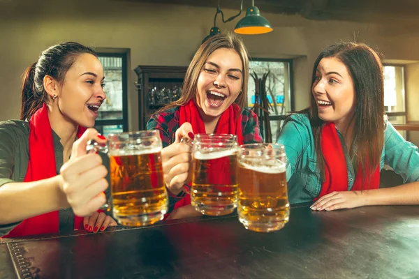 Deporte, gente, ocio, amistad y entretenimiento: aficionados al fútbol felices o amigas bebiendo cerveza y celebrando la victoria en el bar o pub — Foto de Stock