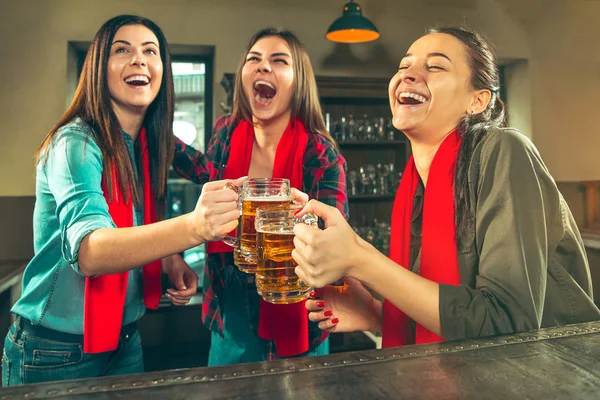 Deporte, gente, ocio, amistad y entretenimiento: aficionados al fútbol felices o amigas bebiendo cerveza y celebrando la victoria en el bar o pub — Foto de Stock