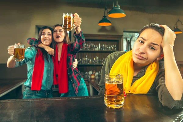 Deporte, gente, ocio, amistad y entretenimiento: aficionados al fútbol felices o amigas bebiendo cerveza y celebrando la victoria en el bar o pub — Foto de Stock