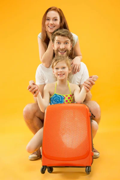 Szczęśliwy rodzic z córka i walizkę w studio samodzielnie na żółtym tle — Zdjęcie stockowe