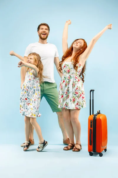 Счастливый родитель с дочерью и чемоданом в студии изолированы на синем фоне — стоковое фото