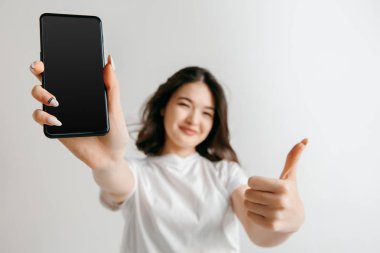 Kendine güvenen rahat Asyalı kız gösteren boş bir ekran cep telefonu portresi