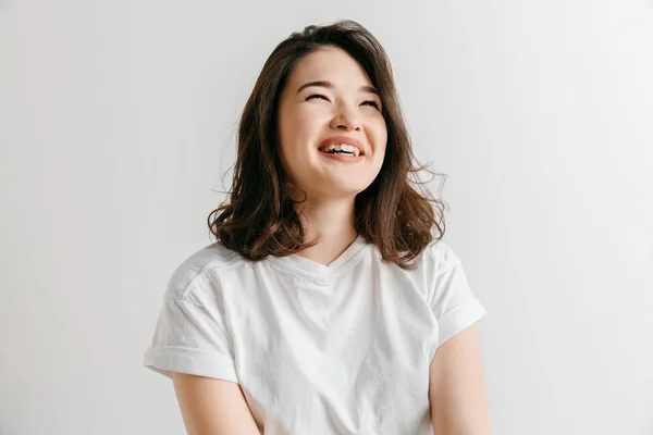 La mujer asiática feliz de pie y sonriendo contra el fondo gris . —  Fotos de Stock