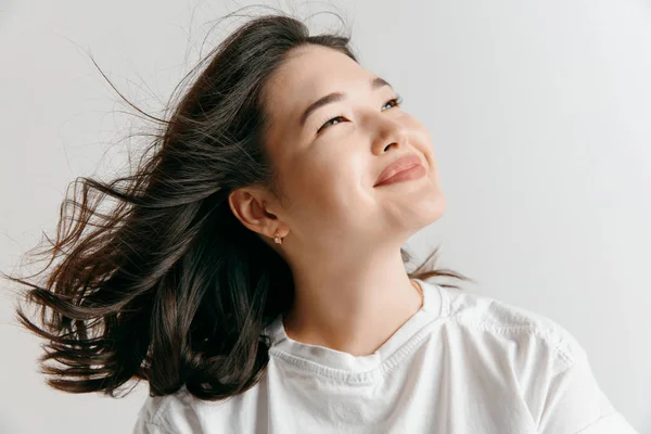 A mulher asiática feliz de pé e sorrindo contra fundo cinza . — Fotografia de Stock