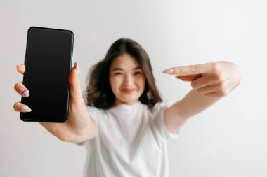 Kendine güvenen rahat Asyalı kız gösteren boş bir ekran cep telefonu portresi