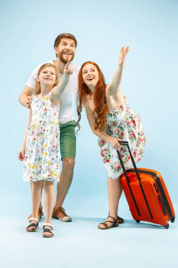 Mutlu anne-baba ile kızı ve bavul üzerinde mavi arka plan izole stüdyosu