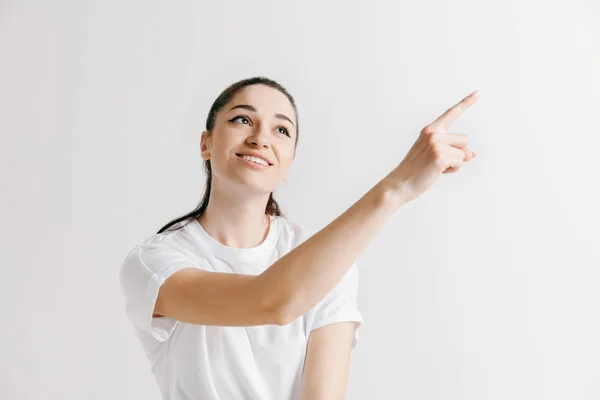 De gelukkige vrouw permanent en glimlachend tegen de grijze achtergrond. — Stockfoto