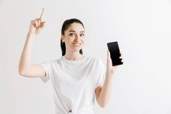 Portrait of a confident casual girl showing blank screen of mobile phone