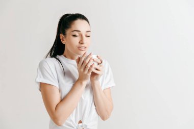 Kahve molası. Kahve fincanı gri arka plan karşı dururken tutan yakışıklı genç