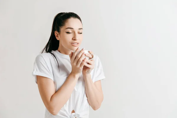 Tomando un descanso para tomar café. Guapo joven sosteniendo la taza de café mientras está de pie sobre fondo gris — Foto de Stock