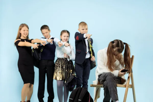 Meisje alleen zittend op een stoel en een daad van pesten lijden. — Stockfoto