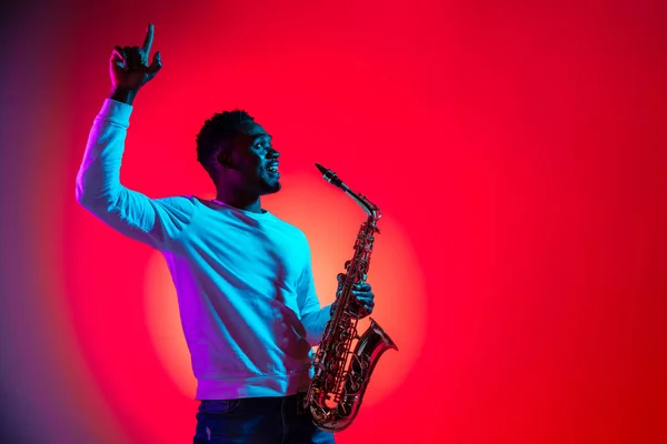 Afrikanisch-amerikanischer Jazzmusiker interagiert mit dem Publikum und hält das Saxophon in der Hand. — Stockfoto