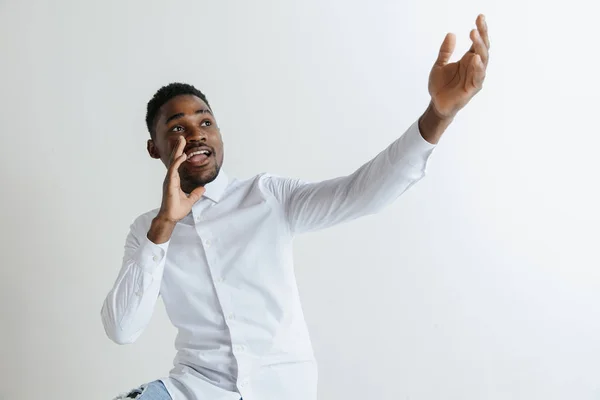 Bonito afro-americano homem em camisa clássica está sorrindo, olhando para a câmera e apontando para longe, contra a parede de tijolo branco — Fotografia de Stock