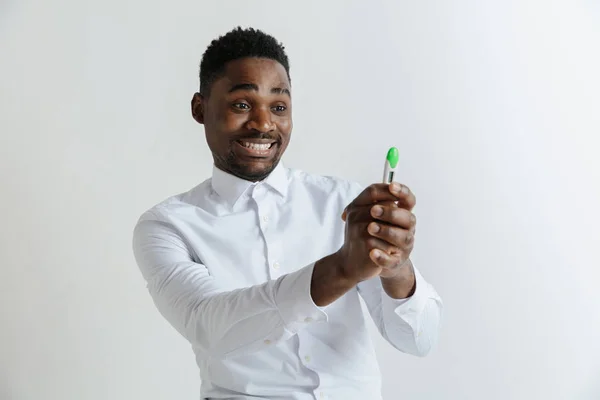 Jovem feliz afro-americano olhando para o teste de gravidez. Bonito homem sorridente inspirado e encantado. Guy satisfeito por causa do resultado do teste de gravidez . — Fotografia de Stock