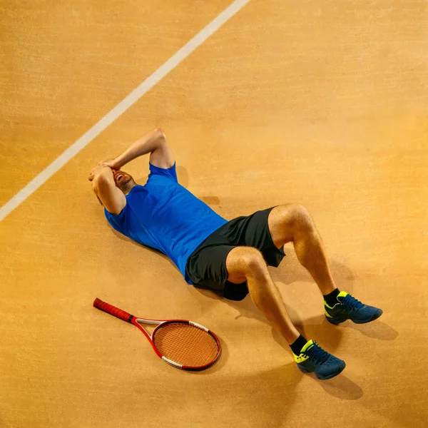 Tennis player crouching down looking defeated and sad