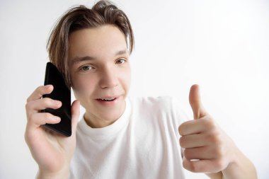 Akıllı telefon ekranını gösteren ve imzalama genç yakışıklı ergen gri arka planda izole ok