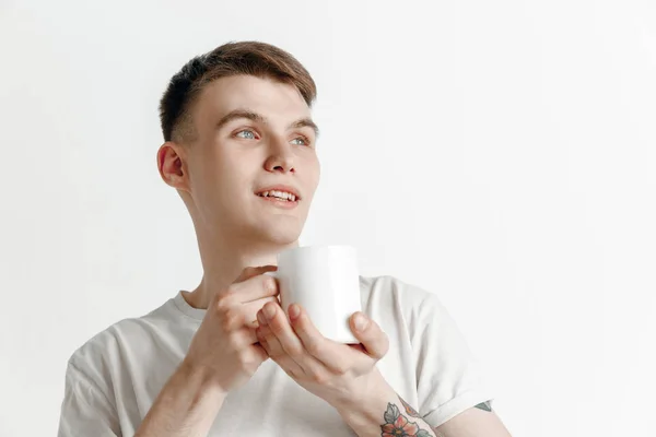 Kaffeepause machen. schöner junger Mann mit Kaffeetasse, lächelnd vor grauem Hintergrund — Stockfoto