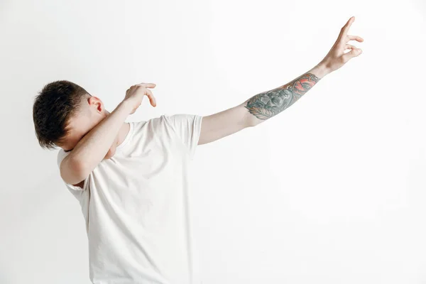 Joven hace el movimiento dab con sus brazos sobre un fondo gris . —  Fotos de Stock