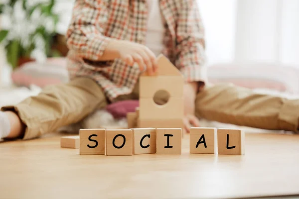 Cubos de madeira com palavra SOCIAL em mãos de menino — Fotografia de Stock