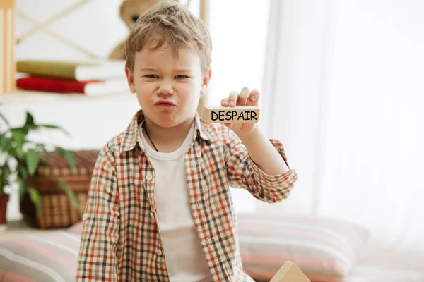 Träkuber med ord förtvivlan i händerna på liten pojke — Stockfoto