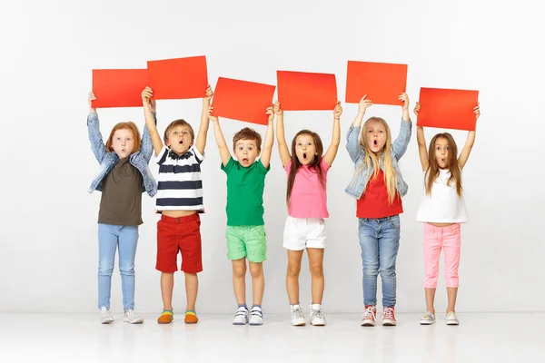 Grupo de niños con pancartas rojas aisladas en blanco — Foto de Stock