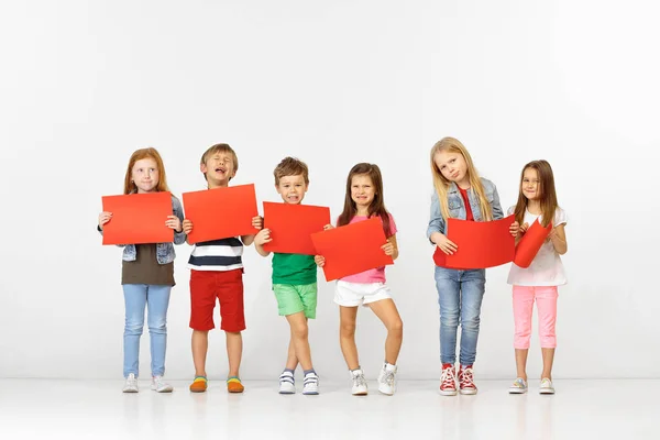 Groep kinderen met rode banners geïsoleerd in wit — Stockfoto