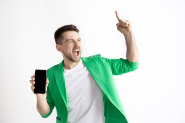 Genç yakışıklı adam akıllı telefon ekranını göstermeyi ve gri arka plan üzerinde izole Tamam imzalama
