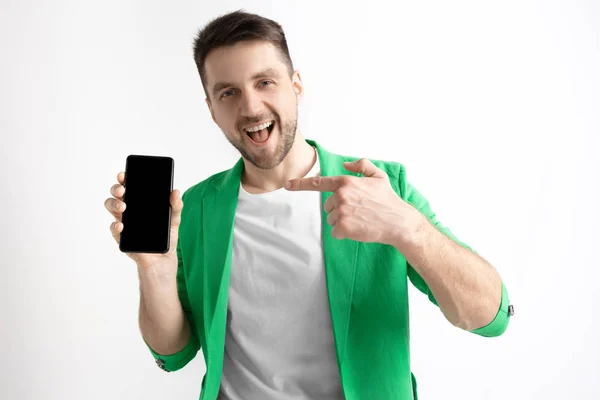 Mladý pohledný muž zobrazení smartphone obrazovky a podepisování Ok izolované na šedém pozadí — Stock fotografie