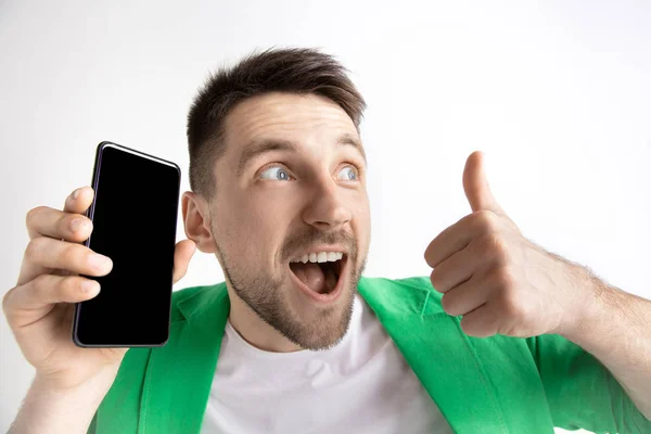 Junger gutaussehender Mann zeigt Smartphone-Bildschirm und signiert ok isoliert auf grauem Hintergrund — Stockfoto