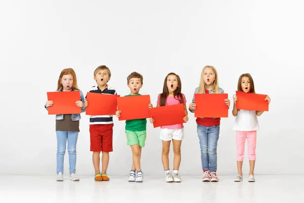 Groep kinderen met rode banners geïsoleerd in wit — Stockfoto