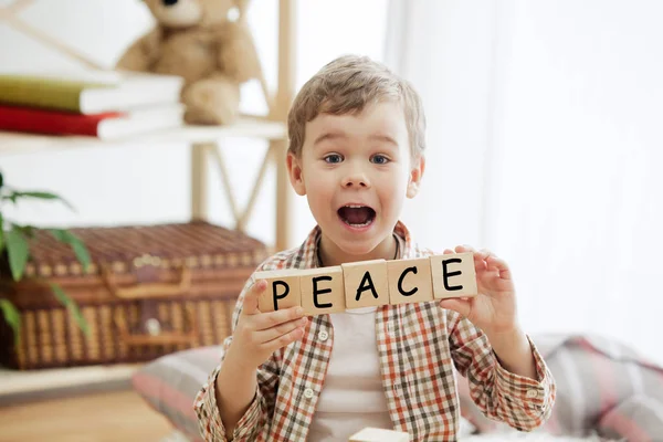 Деревянные кубики со словом МИР в руках маленького мальчика — стоковое фото