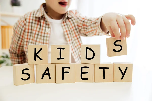 小さな男の子の手に子供の安全単語を持つ木製キューブ — ストック写真