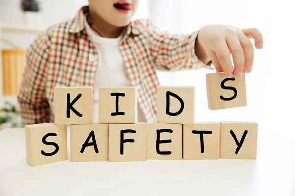 Cubos de madera con palabras NIÑOS SEGURIDAD en manos de niño — Foto de Stock