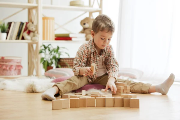Malé dítě sedí na podlaze. Chlapečku na Netlogu s dřevěnými kostkami doma — Stock fotografie