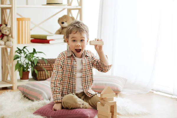 Niña sentada en el suelo. Niño bonito paleando con cubos de madera en casa — Foto de Stock