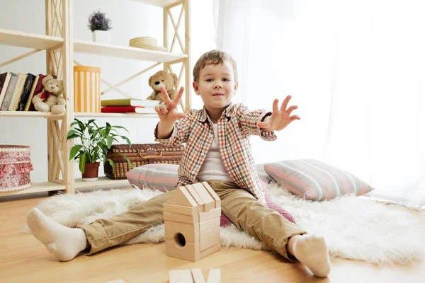 Malé dítě sedí na podlaze. Chlapečku na Netlogu s dřevěnými kostkami doma — Stock fotografie