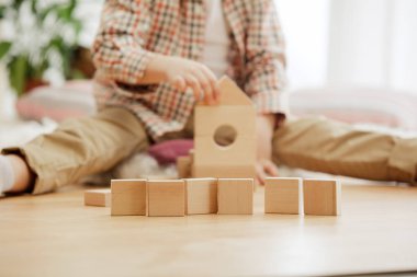 Katta oturan küçük bir çocuk. Evde ahşap küpleriyle yakışıklı palying