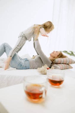 Genç anne ve küçük kızı sarılma ve yatakta öpüşme