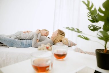 Genç anne ve küçük kızı sarılma ve yatakta öpüşme