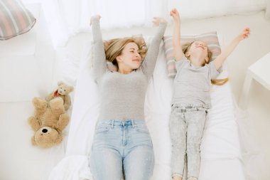 Genç anne ve küçük kızı sarılma ve yatakta öpüşme