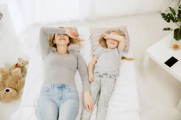 Jeune mère et sa petite fille embrassant et embrassant sur le lit — Photo