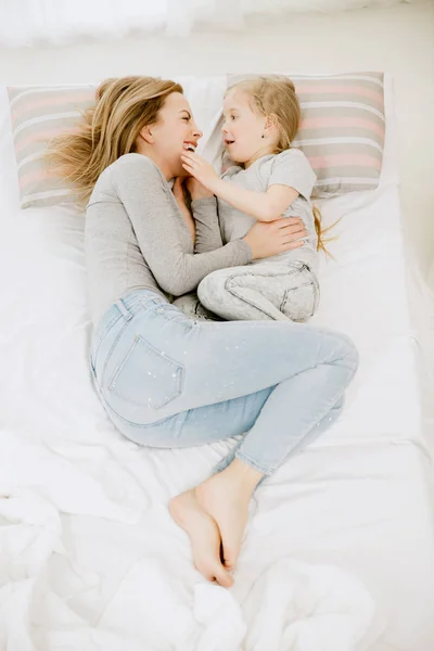 Jeune mère et sa petite fille embrassant et embrassant sur le lit — Photo