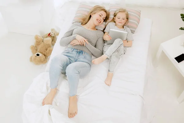 Νεαρή μητέρα και η μικρή κόρη της αγκάλιασμα και το φίλημα στο κρεβάτι — Φωτογραφία Αρχείου